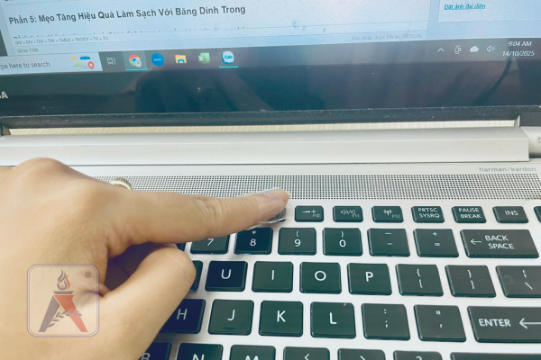 Một ngón tay đang quấn băng dính trong và chạm vào khe giữa các phím máy tính để lấy bụi bẩn.